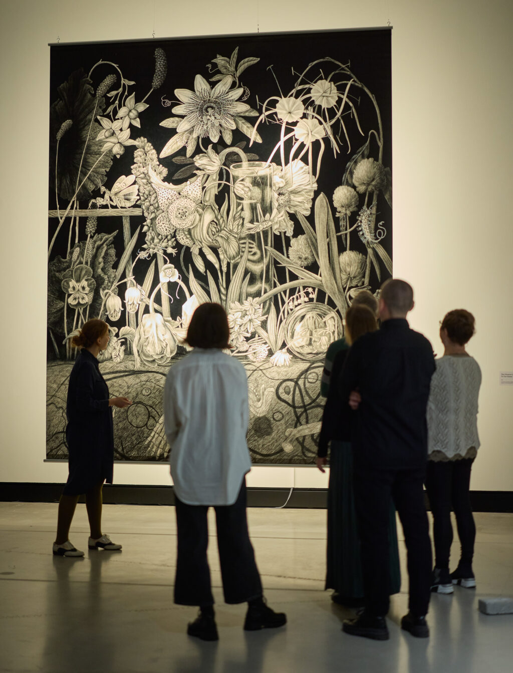Ihmiset katsovat taideteosta näyttelytilassa.