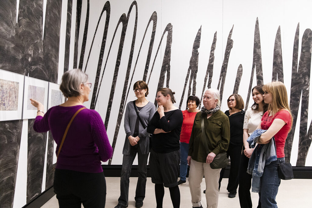 Ryhmä ihmisiä katsomassa taideteoksia.