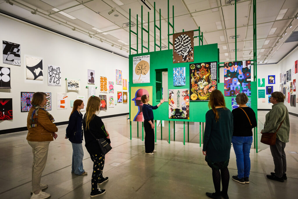 Ryhmä ihmisiä katsomassa julisteita.