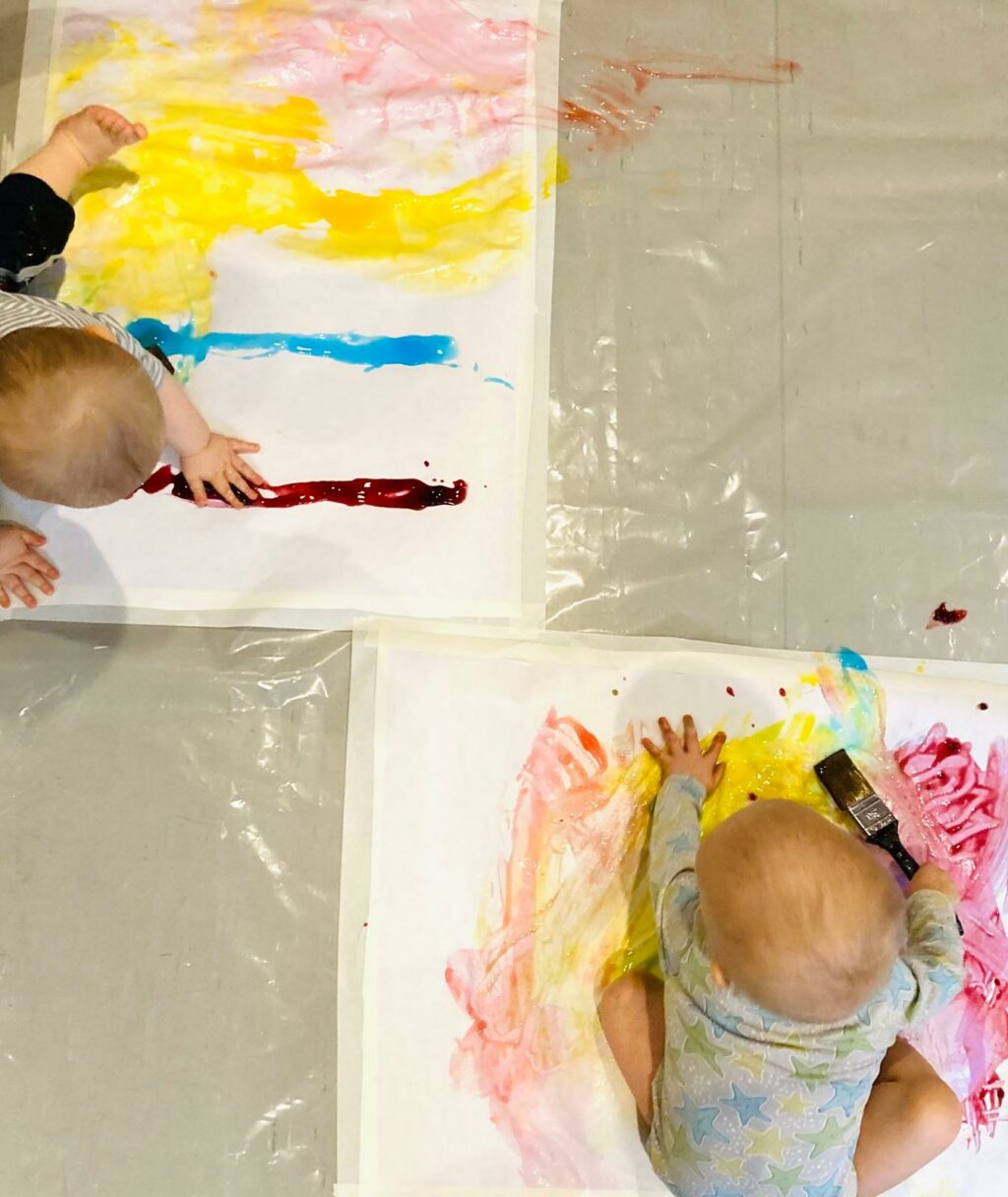 Kaksi vauvaa maalaamassa paperia.