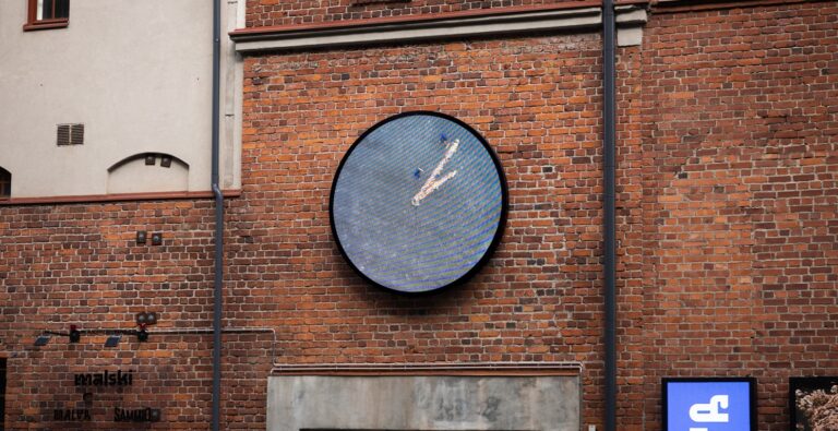 A round clock on a brick wall.